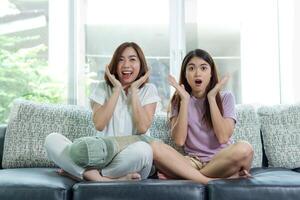 asiatique femme et ami asseoir à Accueil sur canapé lit regarder la télé film. photo