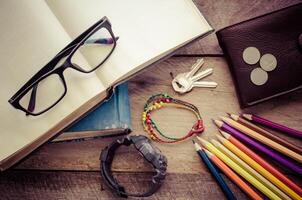 équipement des cahiers, coloré des crayons, montres, lunettes, portefeuille, pièces de monnaie mis sur une en bois sol. photo