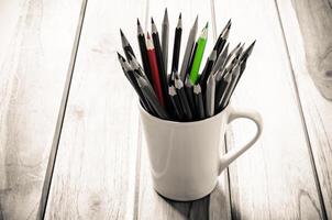 empiler de des crayons dans une verre sur en bois fond, ton sépia photo