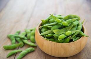 vert des haricots dans en bois tasses mis sur en bois sol. photo