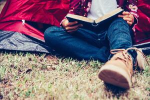 adolescents sont relaxant par en train de lire livres dans tente pique-nique zone dans le jardin. photo