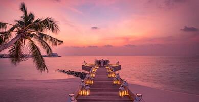 dîner romantique sur la plage avec coucher de soleil, bougies aux feuilles de palmier et ciel et mer au coucher du soleil. vue imprenable, paysage de lune de miel ou de dîner d'anniversaire. horizon de soirée île exotique, romance pour un couple photo