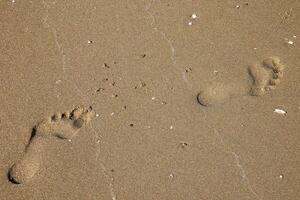 la gauche et droite empreintes en marchant dans le le sable sur le plage photo