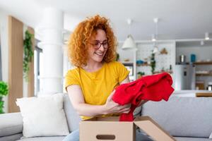 Jeune femme recevoir parcelle à maison. vacances achats en ligne et déballage papier carton boîte. livraison un service pendant convoitise quarantaine. content fille avoir cadeau. mode de vie moment photo