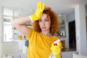 portrait de Jeune fatigué femme avec caoutchouc gants repos après nettoyage un appartement. maison, Entretien ménager concept. photo