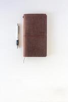 marron cuir couverture Voyage carnet ou carnet de croquis avec stylo sur blanc Contexte. photo