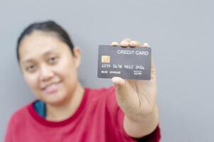 content Jeune femme sourit comme détient le sien crédit carte maquette, utilisé pour en ligne achats et en ligne transactions. photo