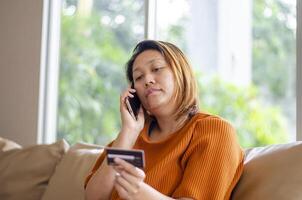 asiatique femme pourparlers sur le téléphone après étant volé argent, escroc pendant un en ligne transaction photo