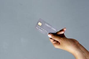 femelle main en portant une noir crédit carte maquette avec Sécurité puce embarqué sur une gris Contexte avec copie espace photo