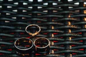 deux mariage anneaux et un engagement bague sur une à carreaux grille. Trois or anneaux de une couple dans l'amour sur une gris arrière-plan.concept de amour.mariage bague photo