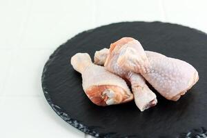 Frais brut poulet jambe pilon sur ardoise assiette photo