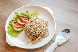 porc frit riz servi dans une restaurant avec en bois sol les tables avec tomates, concombres, oignons verts, frit riz, délicieux nourriture fabriqué de à la vapeur riz. photo