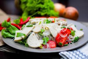 épicé verre nouille salade avec vietnamien saucisse servi dans une gris assiette mettre sur une en bois table et divers des légumes. photo