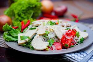 épicé verre nouille salade avec vietnamien saucisse servi dans une gris assiette mettre sur une en bois table et divers des légumes. photo