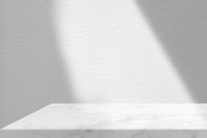table en marbre avec fond de texture de mur en stuc blanc avec faisceau lumineux et ombre, adaptée à la toile de fond de présentation du produit, à l'affichage et à la maquette. photo