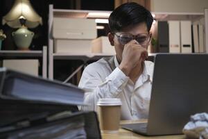 épuisé Jeune homme avec portable dans bureau. photo