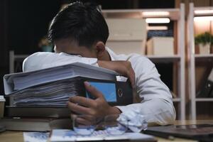 Jeune fatigué homme d'affaire mensonge sur table à nuit bureau. photo