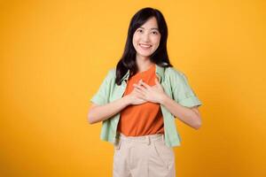 expérience le joie de des économies avec une content Jeune asiatique femme dans sa 30s portant une vert chemise contre une vibrant Jaune toile de fond. l'amour traiter promotion concept photo