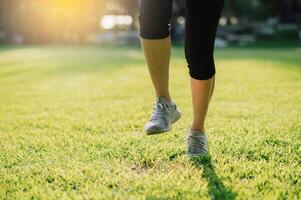 embrasse le concept de bien-être vie. témoin le fermer de une femelle jogger jambes et des chaussures comme elle court pendant le coucher du soleil dans une Publique parc. photo