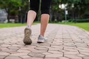 joggeur femme. proche en haut la personne formation sport coureur Jeune femelle chaussure sur marcher chemin dans Publique parc. aptitude jambe et pied exercice athlète. marathon dans la nature. actif en bonne santé mode de vie faire des exercices concept. photo