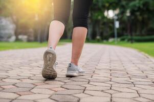 joggeur femme. proche en haut la personne formation sport coureur Jeune femelle chaussure sur marcher chemin dans Publique parc. aptitude jambe et pied exercice athlète. marathon dans la nature. actif en bonne santé mode de vie faire des exercices concept. photo