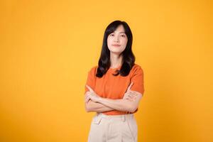 déchaîner le Puissance de confiance comme une Jeune asiatique femme dans sa 30s, enfiler un Orange chemise, expositions franchi bras signe geste sur Jaune Contexte. photo