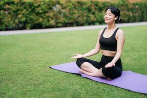 interne paix dans la nature. asiatique femme 30s dans yoga pose au milieu de une serein vert paysage. bien-être, tranquillité, et conscient relaxation. photo