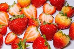 beaucoup des fraises et moitié des fraises sur une blanc Contexte photo