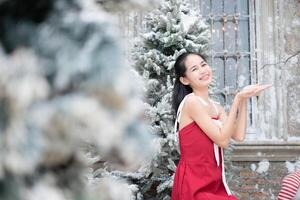 portrait de adolescent fille dans une rouge robe détendu et souriant dans une neigeux cour. photo