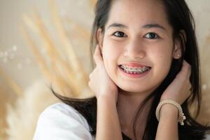 portrait de une Jeune asiatique femme avec un appareil dentaire sur sa les dents photo