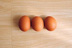 3 poulet des œufs avec une en bois Contexte. photo