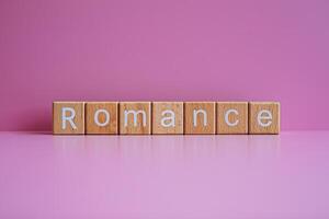 en bois blocs forme le texte romance contre une rose Contexte. photo