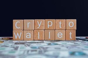 en bois blocs avec le texte crypto portefeuille sur une noir Contexte et crypto billets de banque épars sur le sol. photo