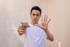 indonésien homme rejeté pose et geste avec tenir le argent. le photo est adapté à utilisation pour homme expression La publicité et mode la vie style.