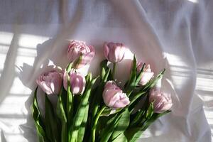 une bouquet de magnifique délicat Frais lilas tulipes mensonges sur une blanc en tissu photo