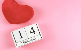 en bois calendrier février 14 avec rouge cœur forme oreiller sur rose arrière-plan, valentines journée concept. photo