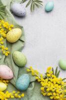 coloré Pâques des œufs et mimosa fleurs sur béton Contexte. photo