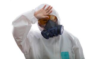 une femme se sent fatiguée dans un vêtement de protection chimique et un masque antigaz avec des lunettes jaunes sur fond blanc, une femme scientifique en tenue de sécurité photo