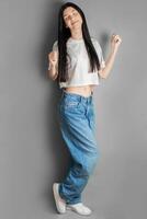 plein longueur portrait de une Jeune fille dans une blanc T-shirt et jeans. photo