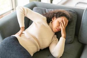 femme latine allongée sur un canapé avec une sensation de mal de dos