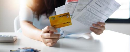 main de femme tenant une carte de crédit et une facture accumulée, une dette et un concept de faillite