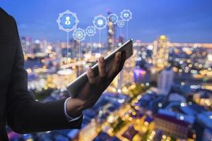 concept commercial et technologique, homme d'affaires tenant une tablette sur fond de paysage de ville de nuit