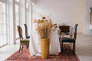 table ensemble pour action de grâces avec ancien chaises de différent formes et couleurs dans une brillant vivant pièce avec français les fenêtres photo