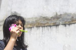 une fille tenant une machine à bulles et les soufflant. photo