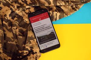 Kyiv, Ukraine - 4 peut, 2023 24tv ukrainien nouvelles portail sur téléphone intelligent écran avec ukrainien drapeau et camouflage en tissu photo