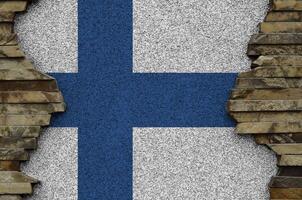 Finlande drapeau représenté dans peindre couleurs sur vieux pierre mur fermer. texturé bannière sur Roche mur Contexte photo