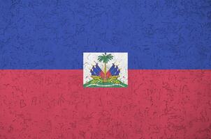 drapeau d'haïti représenté dans des couleurs de peinture vives sur un vieux mur de plâtrage en relief. bannière texturée sur fond rugueux photo