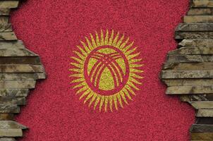 Kirghizistan drapeau représenté dans peindre couleurs sur vieux pierre mur fermer. texturé bannière sur Roche mur Contexte photo