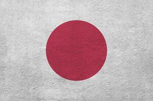 Japon drapeau représenté dans brillant peindre couleurs sur vieux le soulagement plâtrage mur. texturé bannière sur rugueux Contexte photo