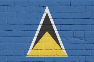 Saint lucia drapeau représenté dans peindre couleurs sur vieux brique mur. texturé bannière sur gros brique mur maçonnerie Contexte photo